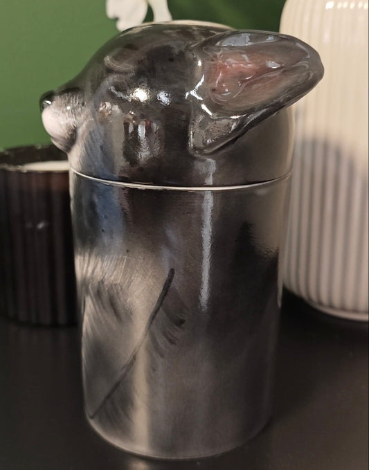 Left-side view of a hand-painted black dog memorial urn with folded-ear detail