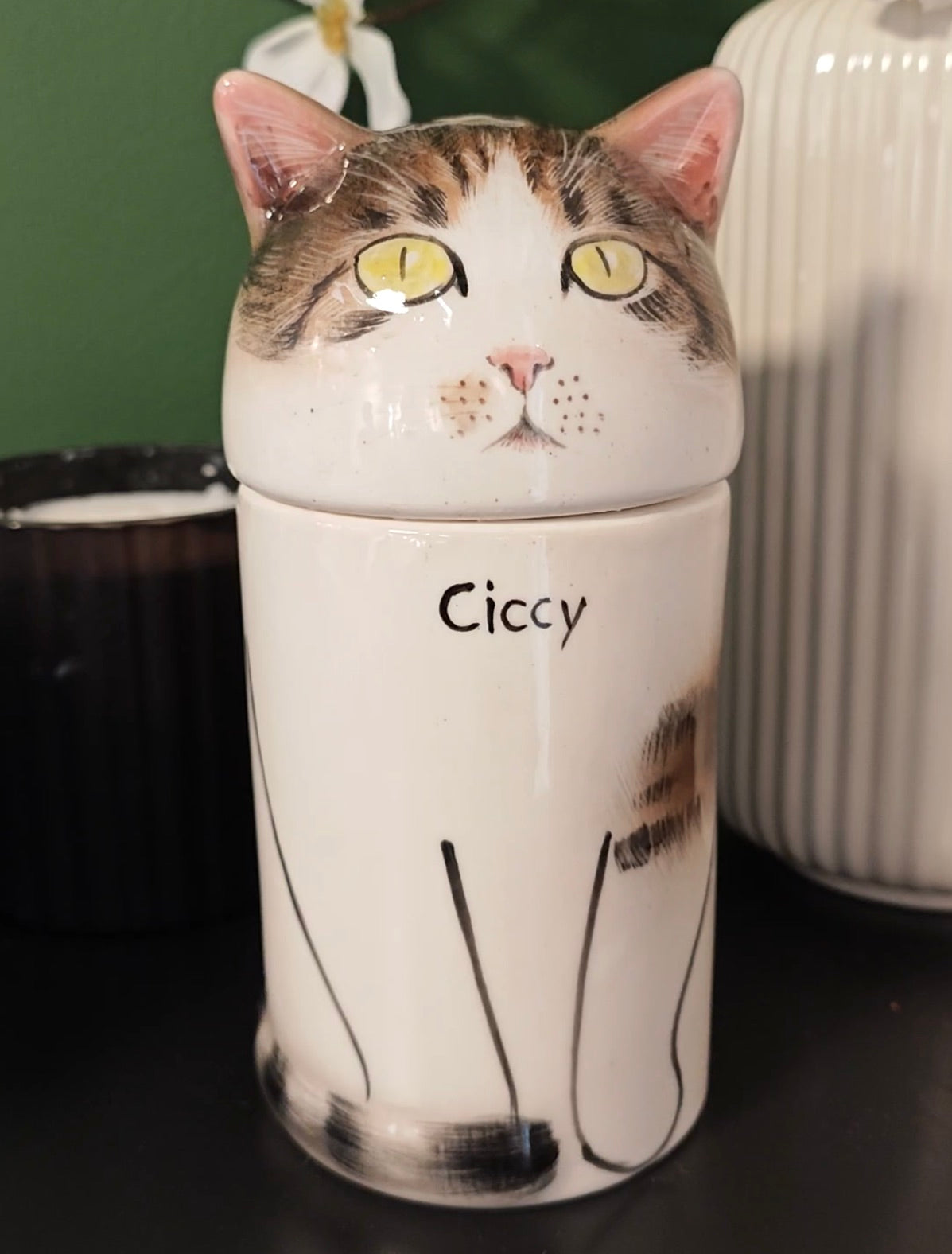 Front view of a personalized tabby-and-white cat urn for ashes with yellow-green eyes and a hand-painted name