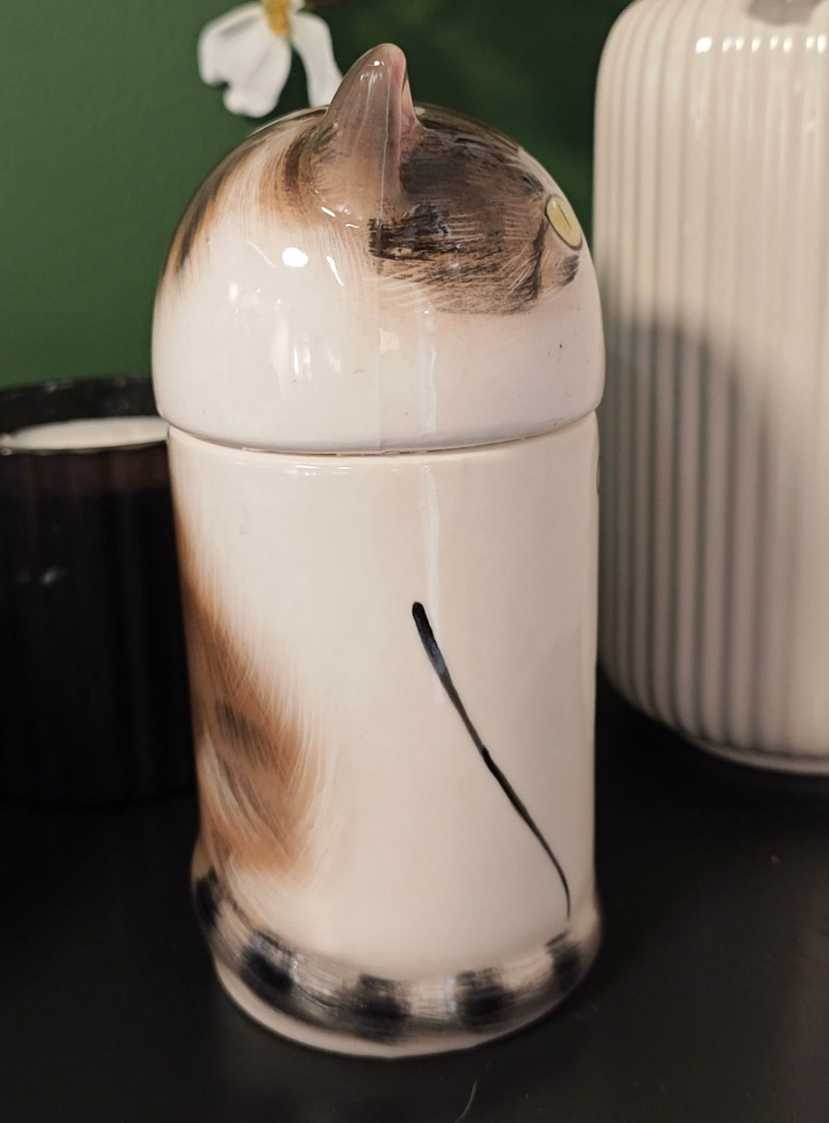 Right-side view of a small tabby-and-white ceramic cat urn showing custom body markings and tail detail
