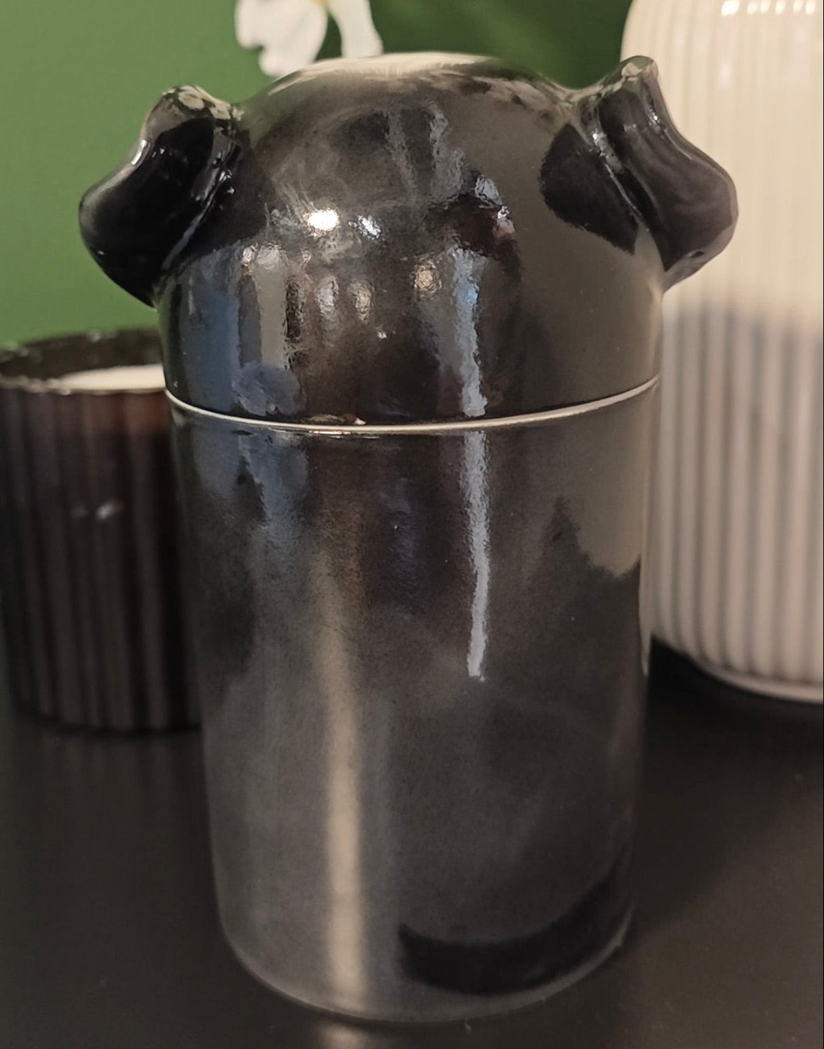 Rear view of a hand-painted black dog urn for ashes with folded ears and tail detail